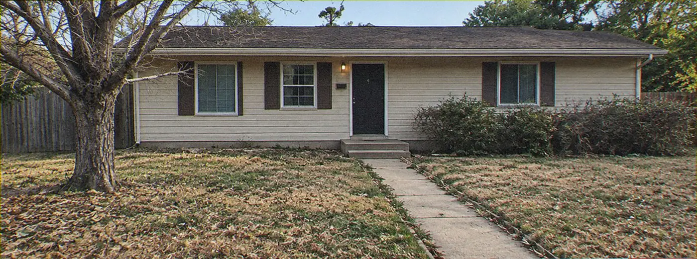 Front yard before: patchy dead grass under a bare oak, leaves everywhere, overgrown shrubs against the house
